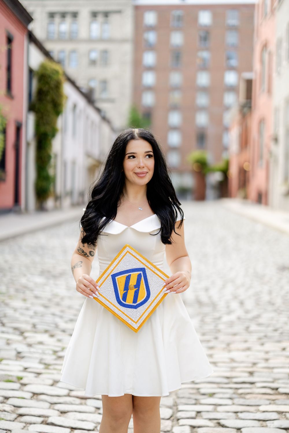 A graduation photoshoot on a cobblestone street featuring decorative letter blocks and a white dress.