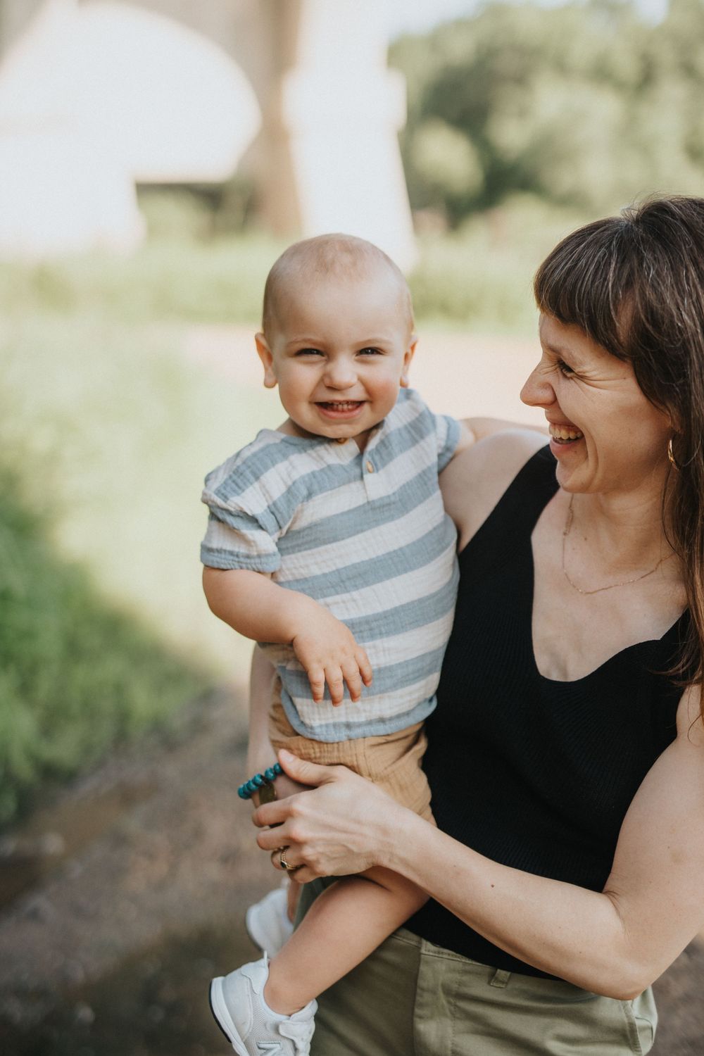 A candid moment of shared laughter between parent and baby outdoors on a sunny day.
