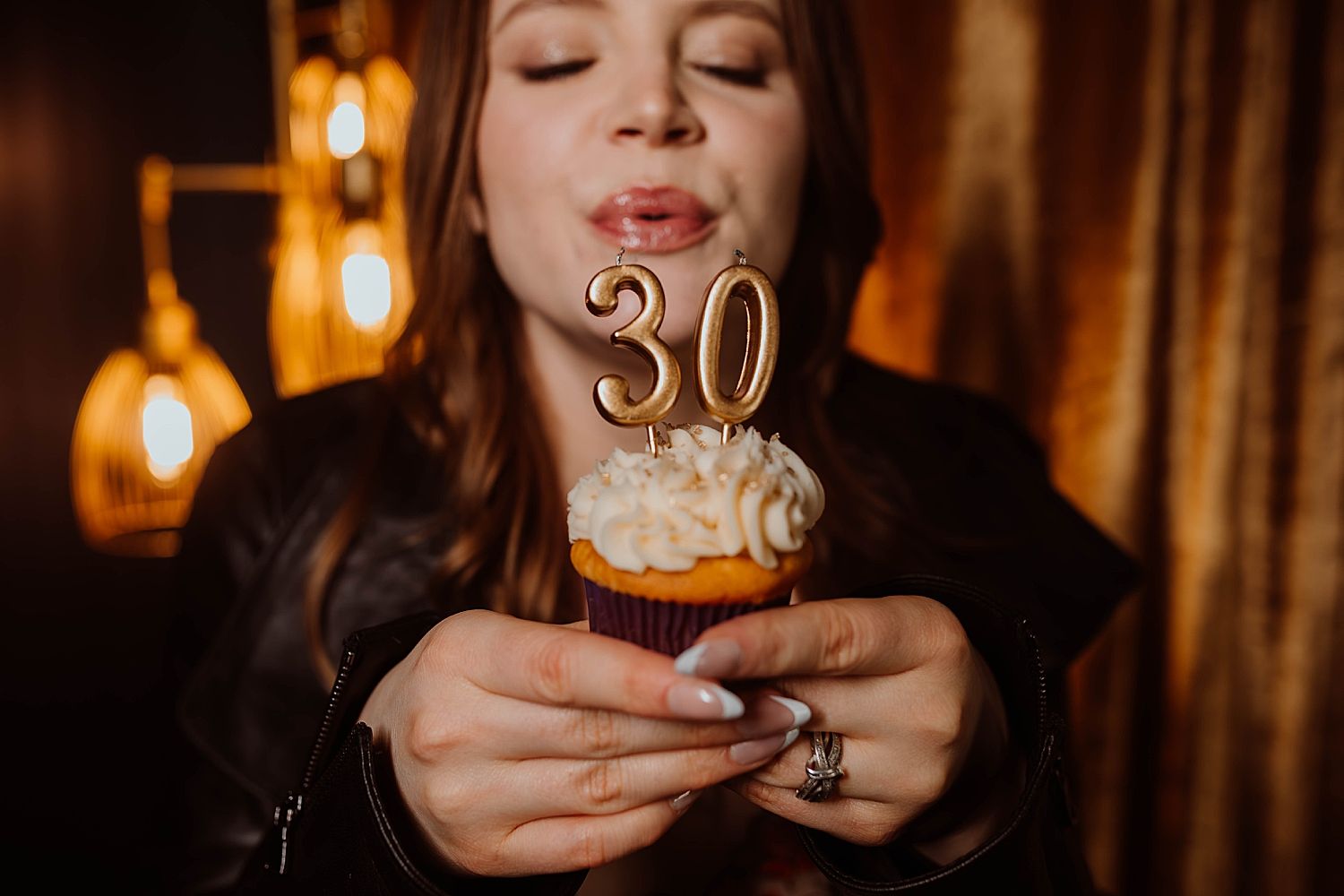 Woman holds up 30 birthday cupcake after learning what to look for when choosing a boudoir photographer
