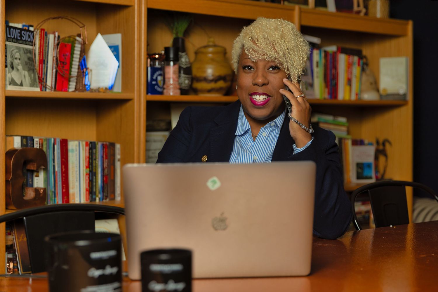 Office meeting space with bookshelves and laptops visible on wooden table.