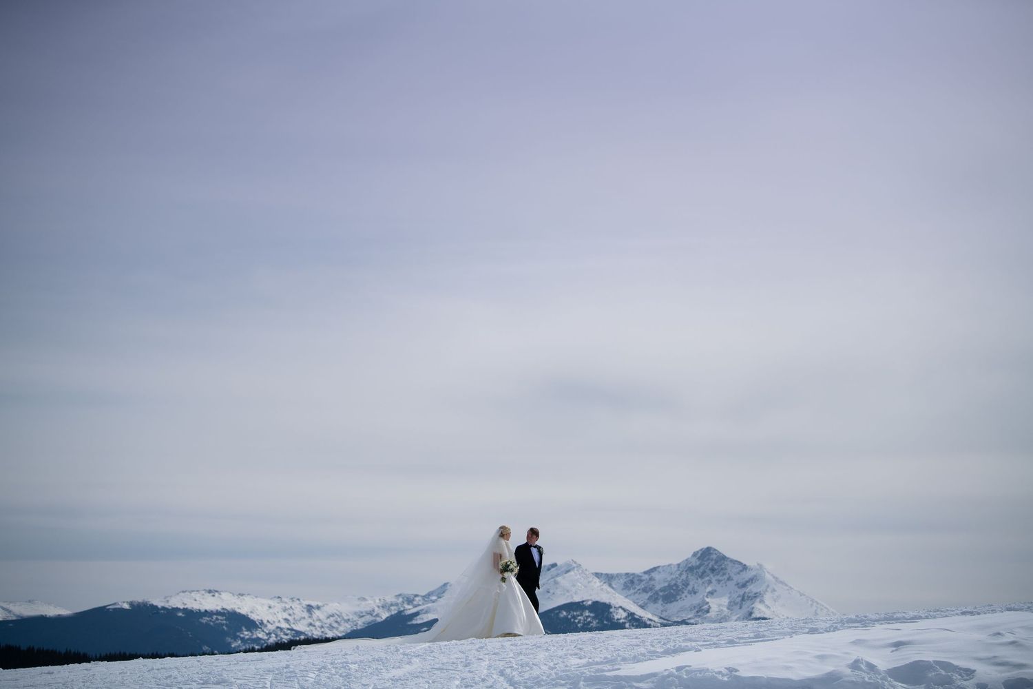 Snowy mountain landscape wedding photos with dramatic winter peaks in background.