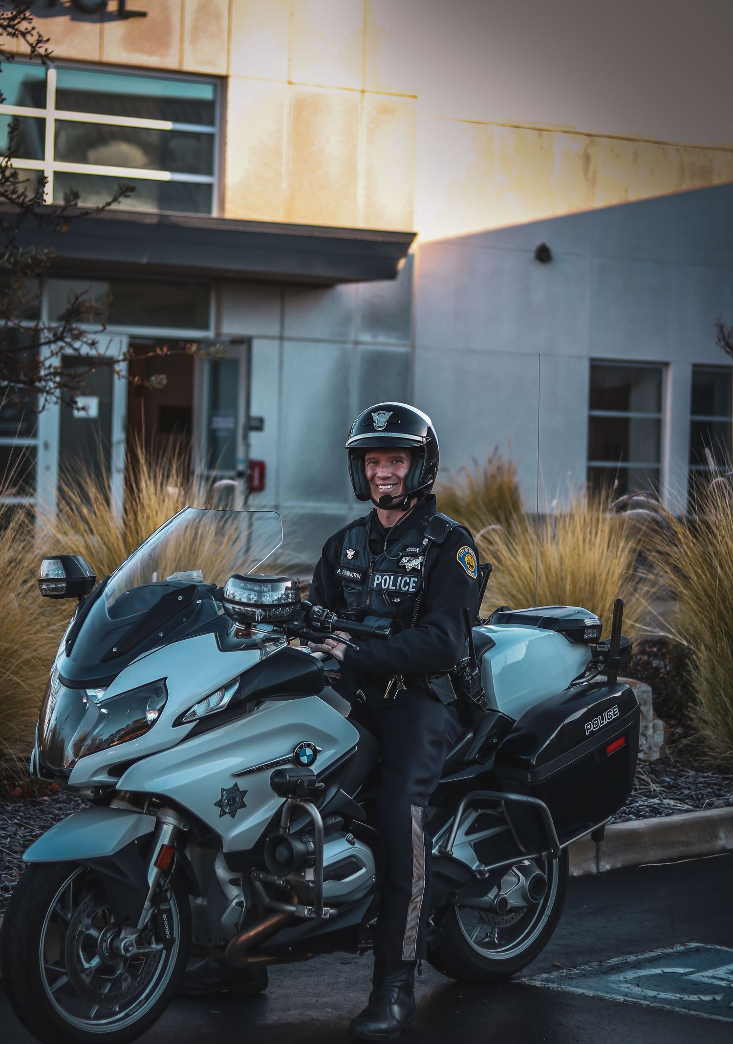 Police officers on motorcycles parked outside a building at dusk.