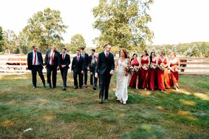 Wedding party members stand together on a grassy lawn during an autumn outdoor celebration at the Stables in Northwest, Ohio.