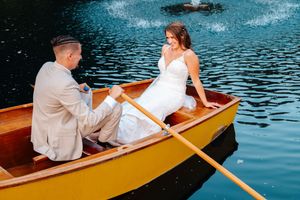 A couple enjoys a romantic canoe ride across tranquil waters in a wooden boat.
