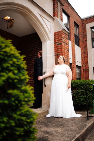 A couple stands in front of a brick building entrance with an arched doorway and white stone trim in Bowling Green, Ohio.