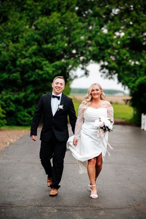 A happy couple walking together on their wedding day, with lush greenery in the background at Bloom&Bower in Risingsun, Ohio.