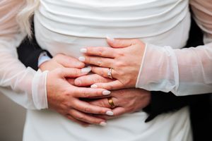 Close-up view of hands with wedding rings on white fabric showing romantic details of a wedding ceremony.