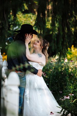 A romantic wedding couple shares intimate kisses in a lush garden setting with soft natural lighting and greenery.