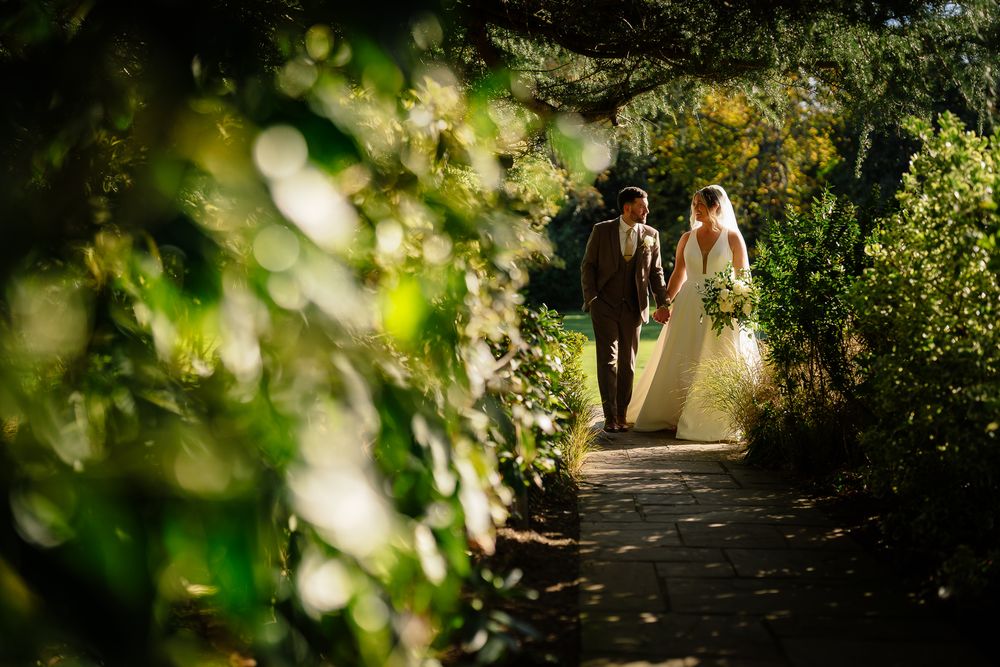 Garden pathway wedding portrait framed by lush greenery and natural light.