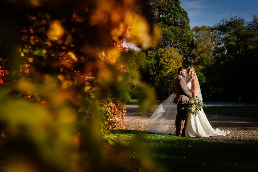 Romantic autumn wedding portrait with golden foliage in the foreground.