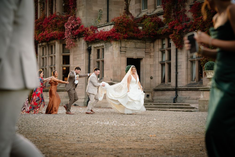 Wedding party having fun outside historic building with red climbing vines.