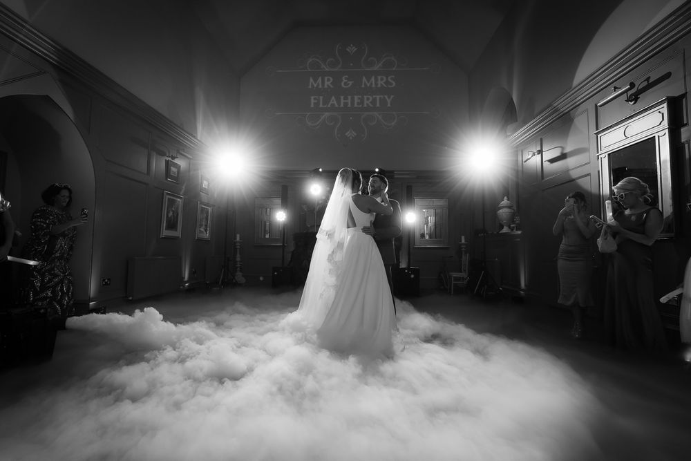 Dramatic first dance on misty dance floor with atmospheric lighting.