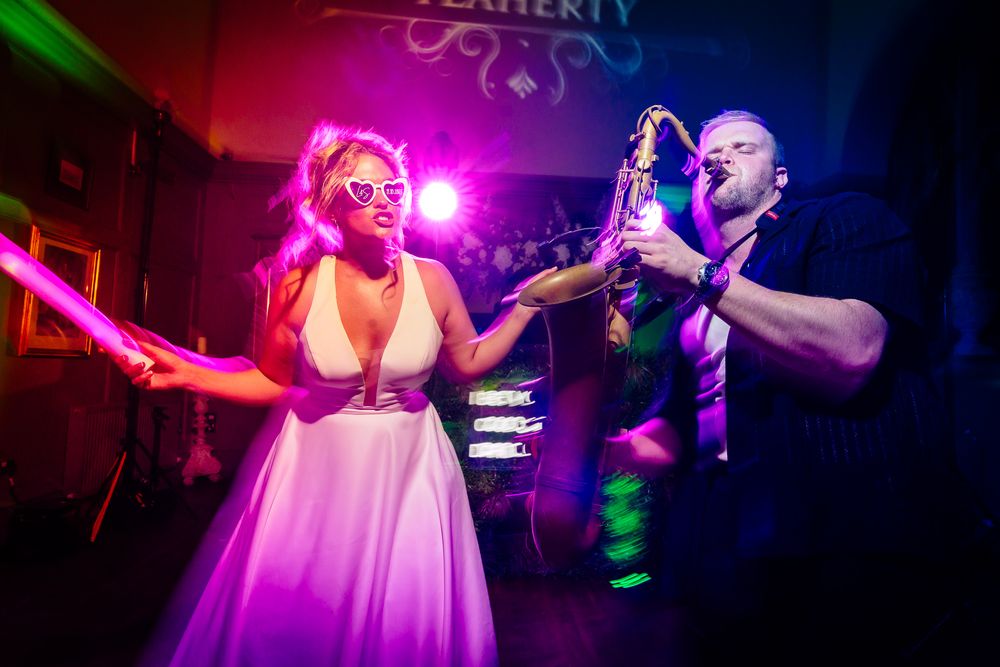 Couple dancing together under dramatic pink and green nightclub lighting during their wedding reception.