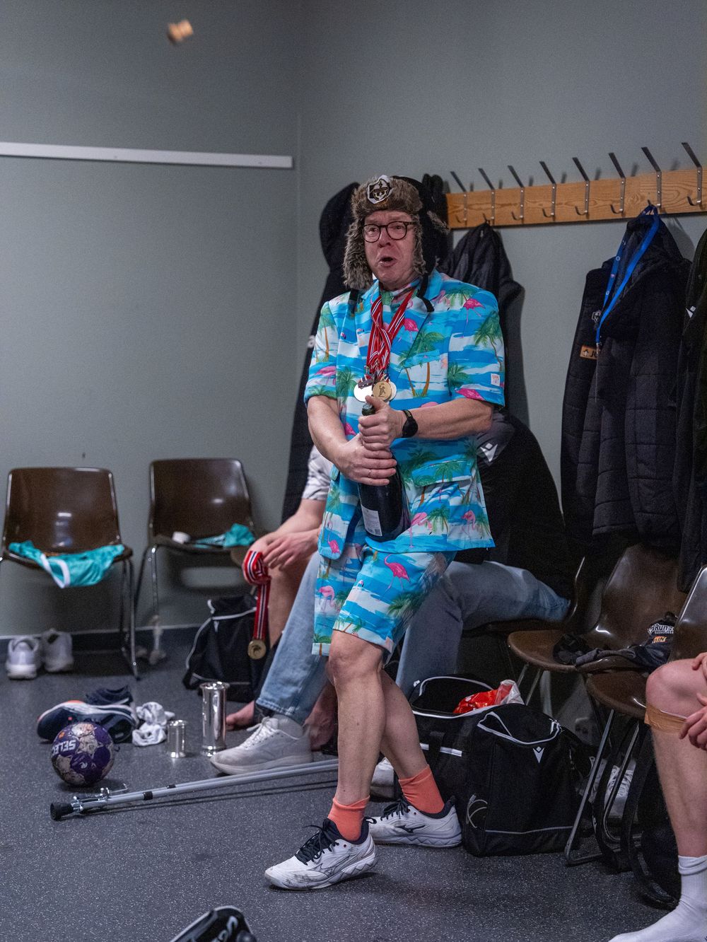 Person in a bright tropical print shirt sitting in what appears to be a backstage or green room area.