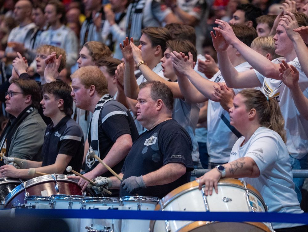 Enthusiastic crowd watching and cheering during an indoor sports event.