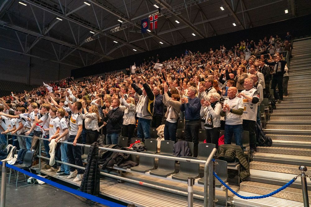 Large crowd of students fills bleachers in gymnasium during school assembly or sporting event.