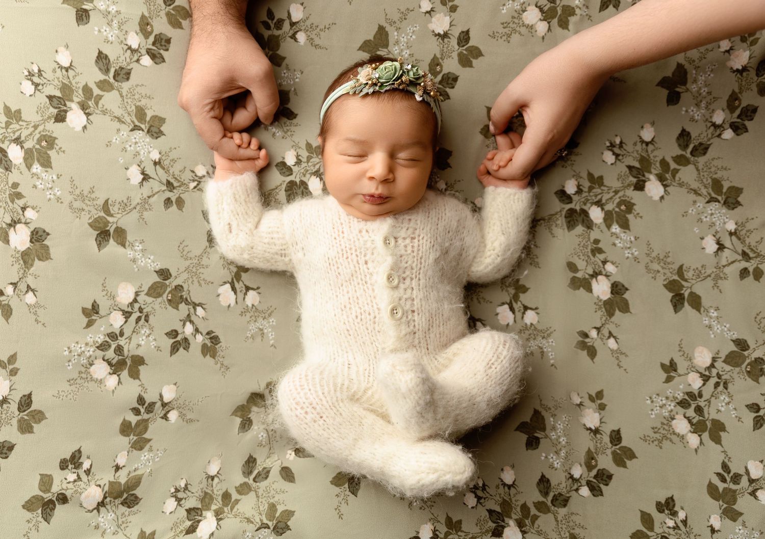 Tilton NH newborn photography of a sleeping baby in a cream knit outfit, fine art studio portrait with soft floral backdrop.