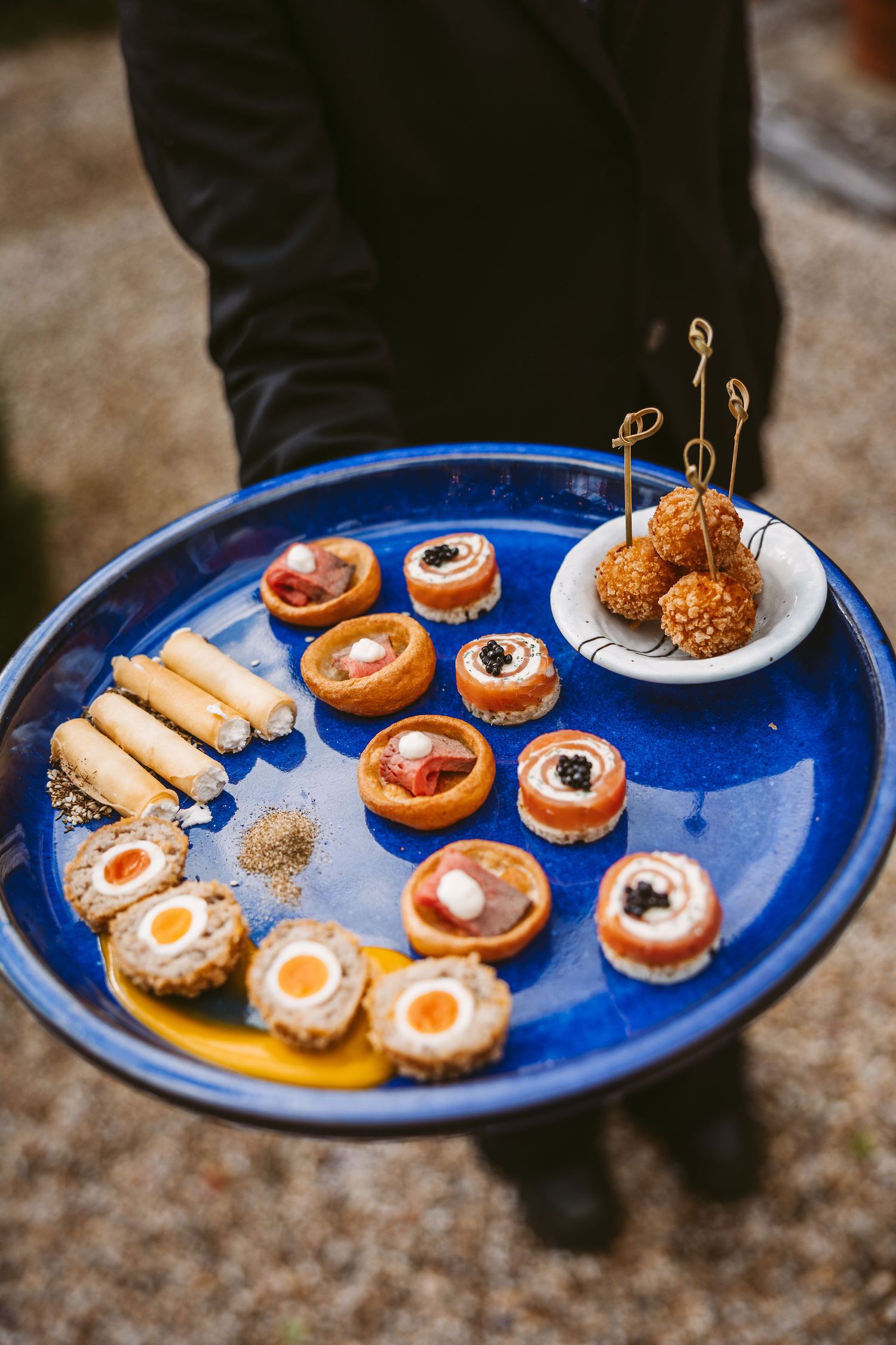 Assorted appetizers and desserts served on bright blue plates including small pastries and finger foods.