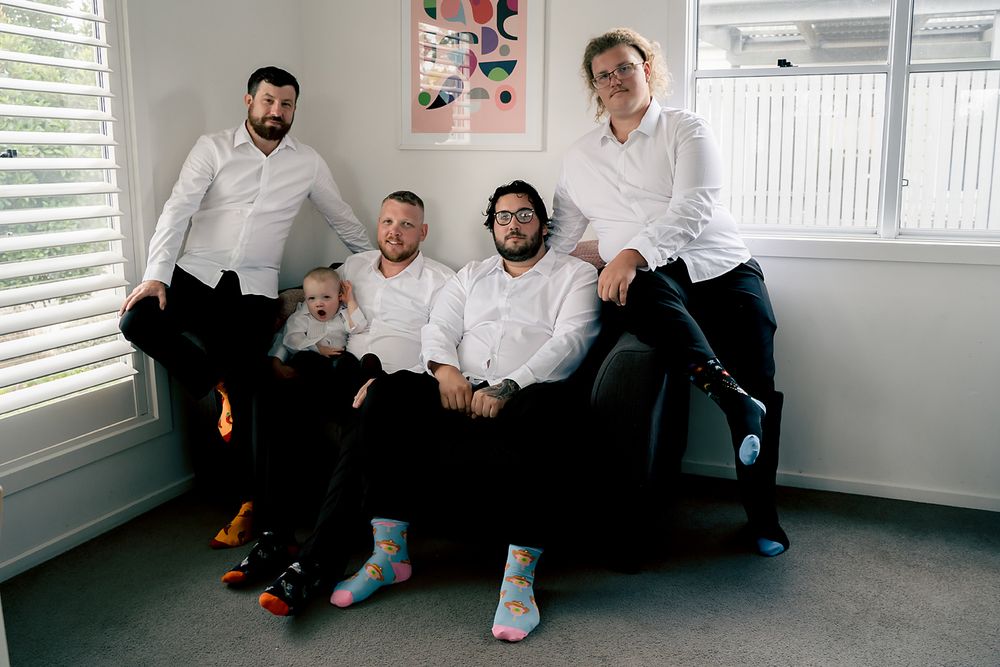 Group of people sitting casually together in a bright modern room with white walls and shuttered windows.
