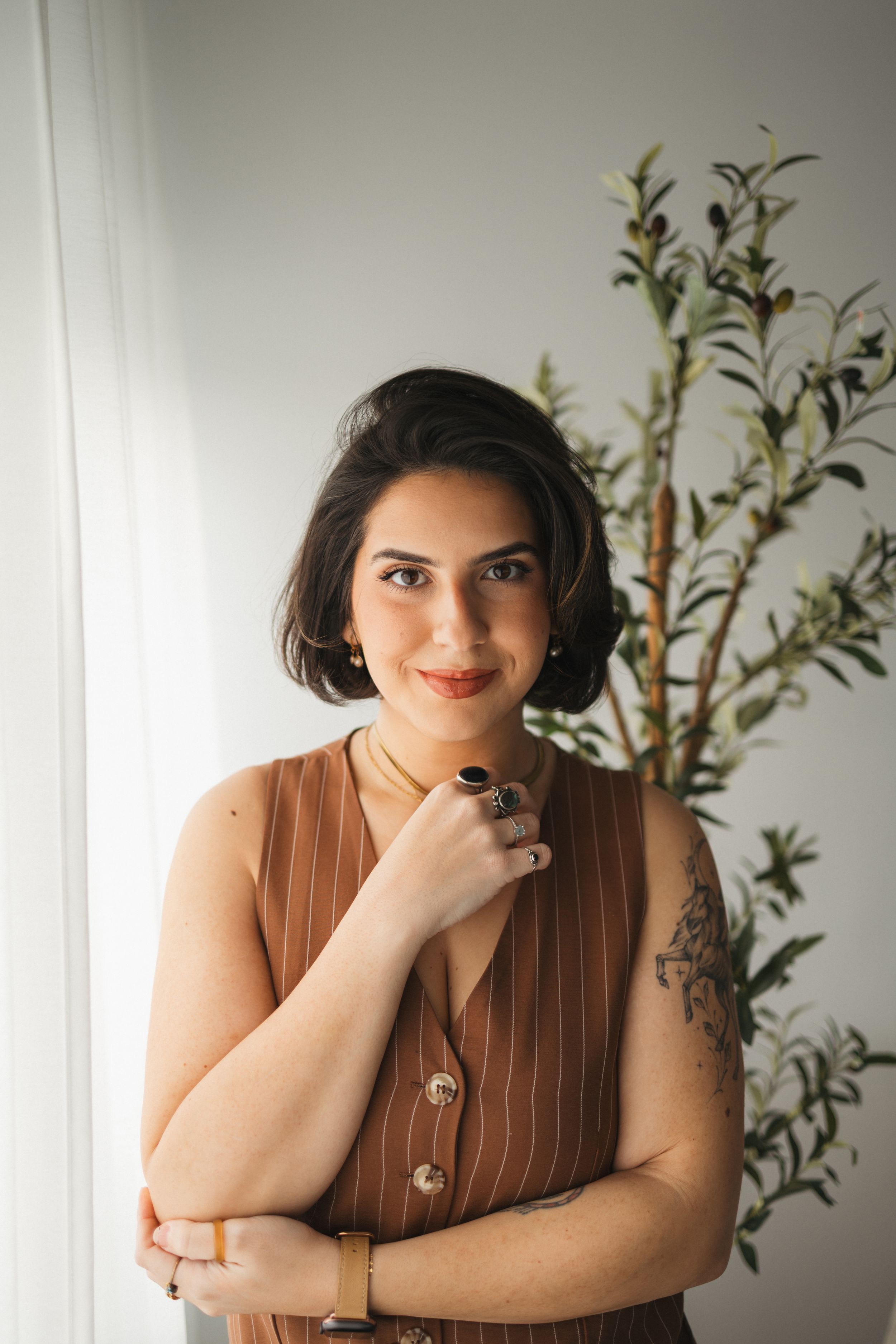 Portrait session featuring brown pinstripe outfit and natural greenery backdrop.