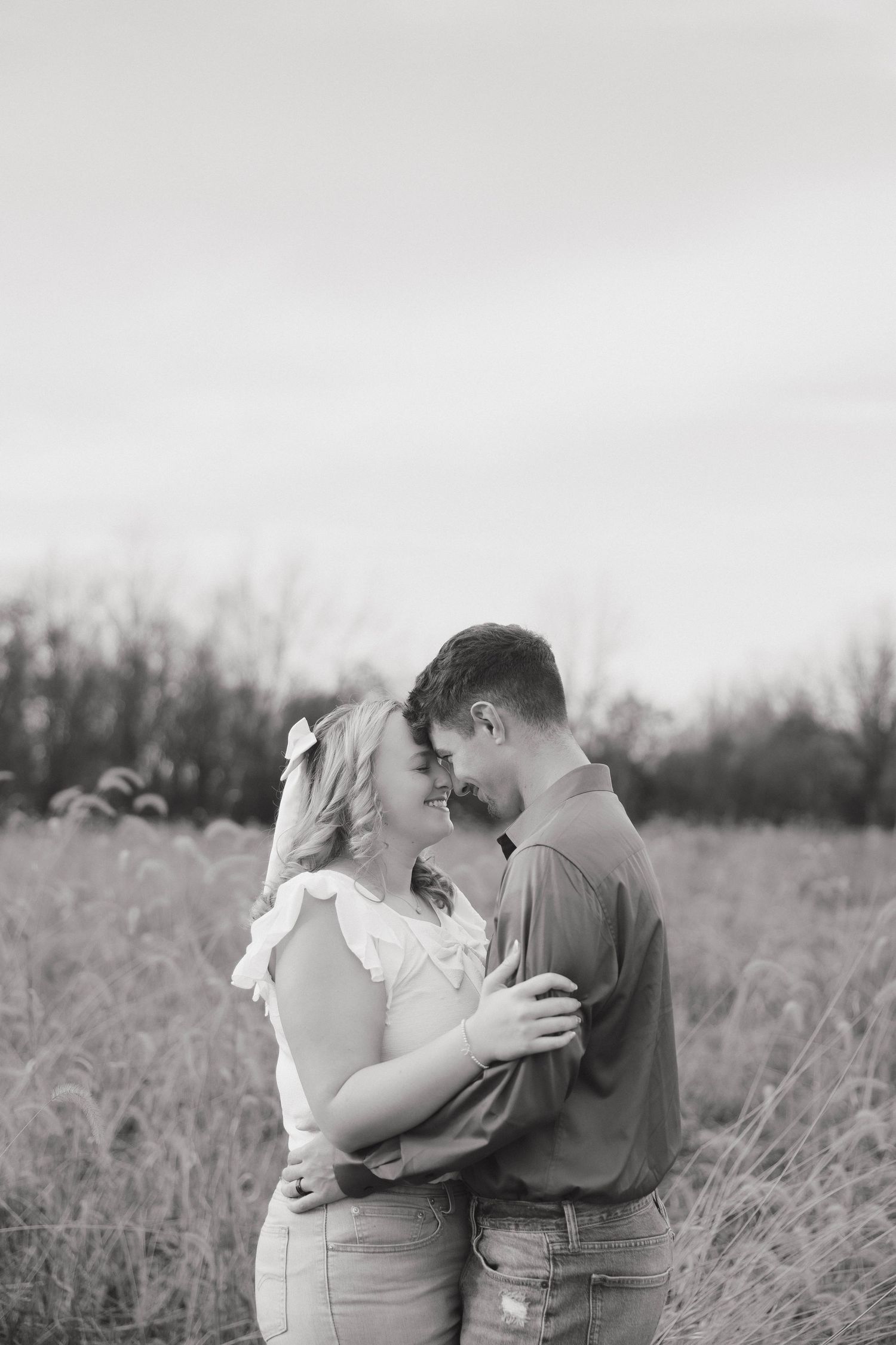 A romantic couple embraces in a field of tall grass, shown in a black and white photo series.