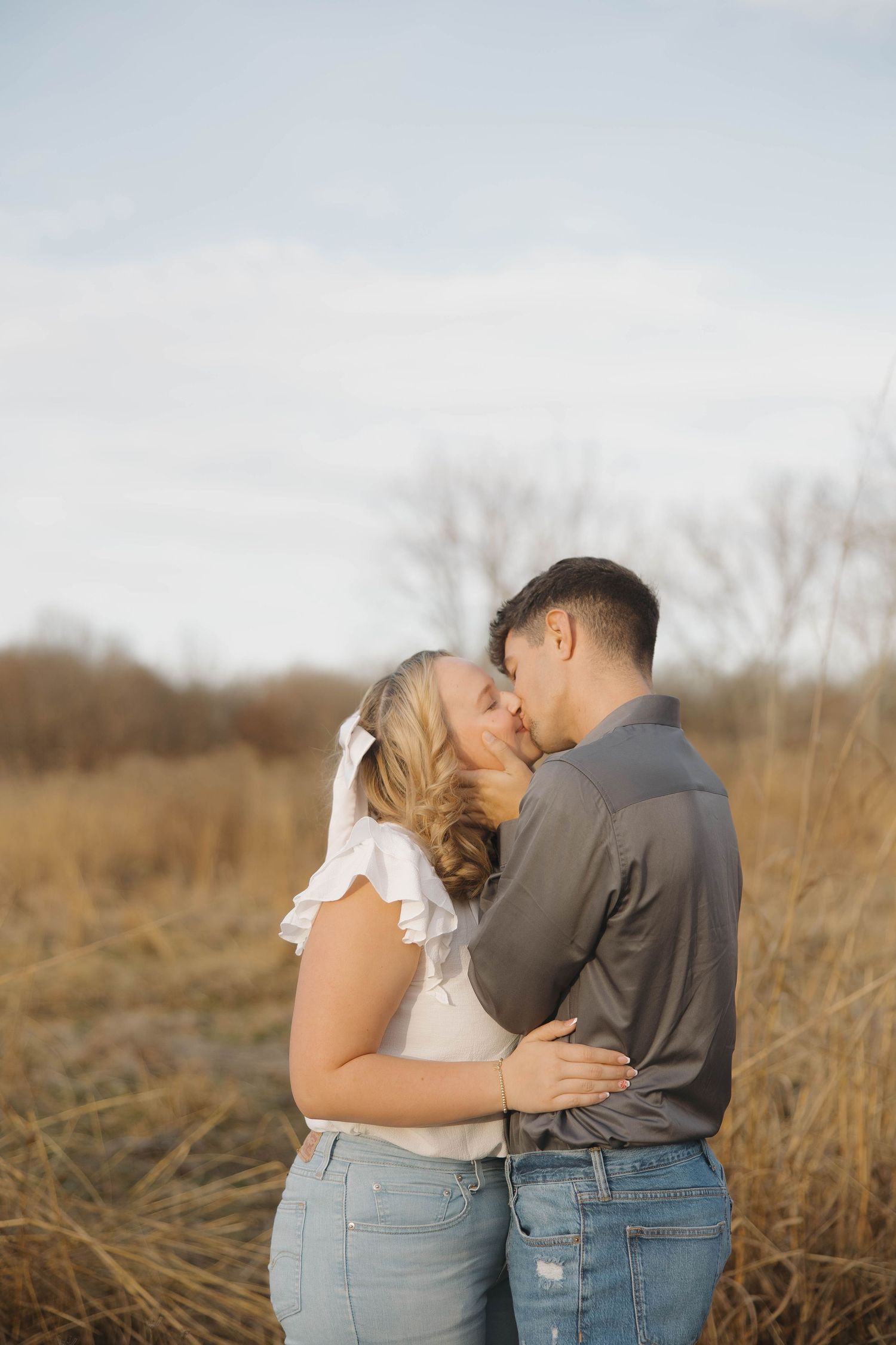 A tender moment between a couple embracing in a sunlit field during golden hour.