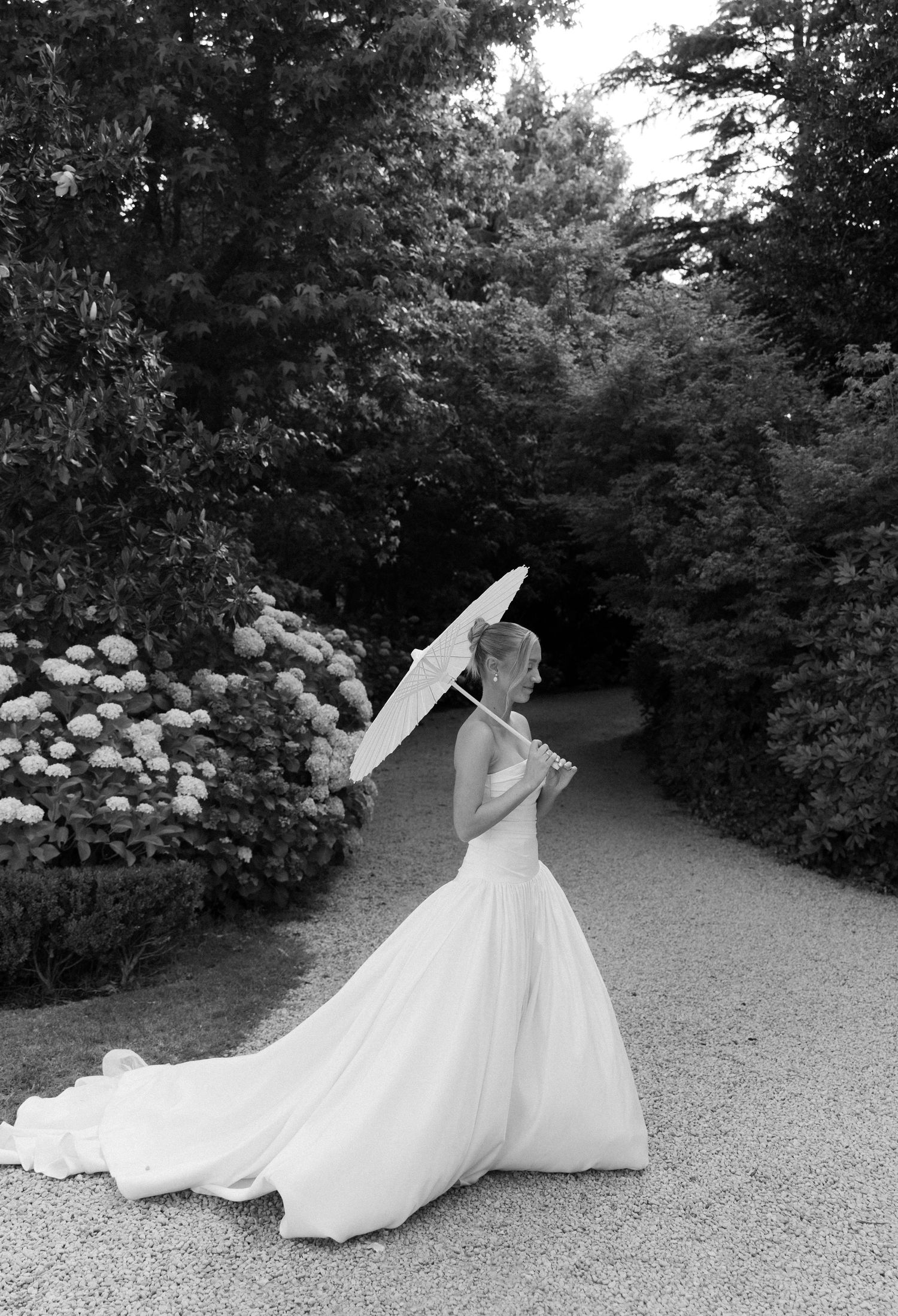 Black and white sequence of a bride in flowing white gown twirling gracefully in a garden path.