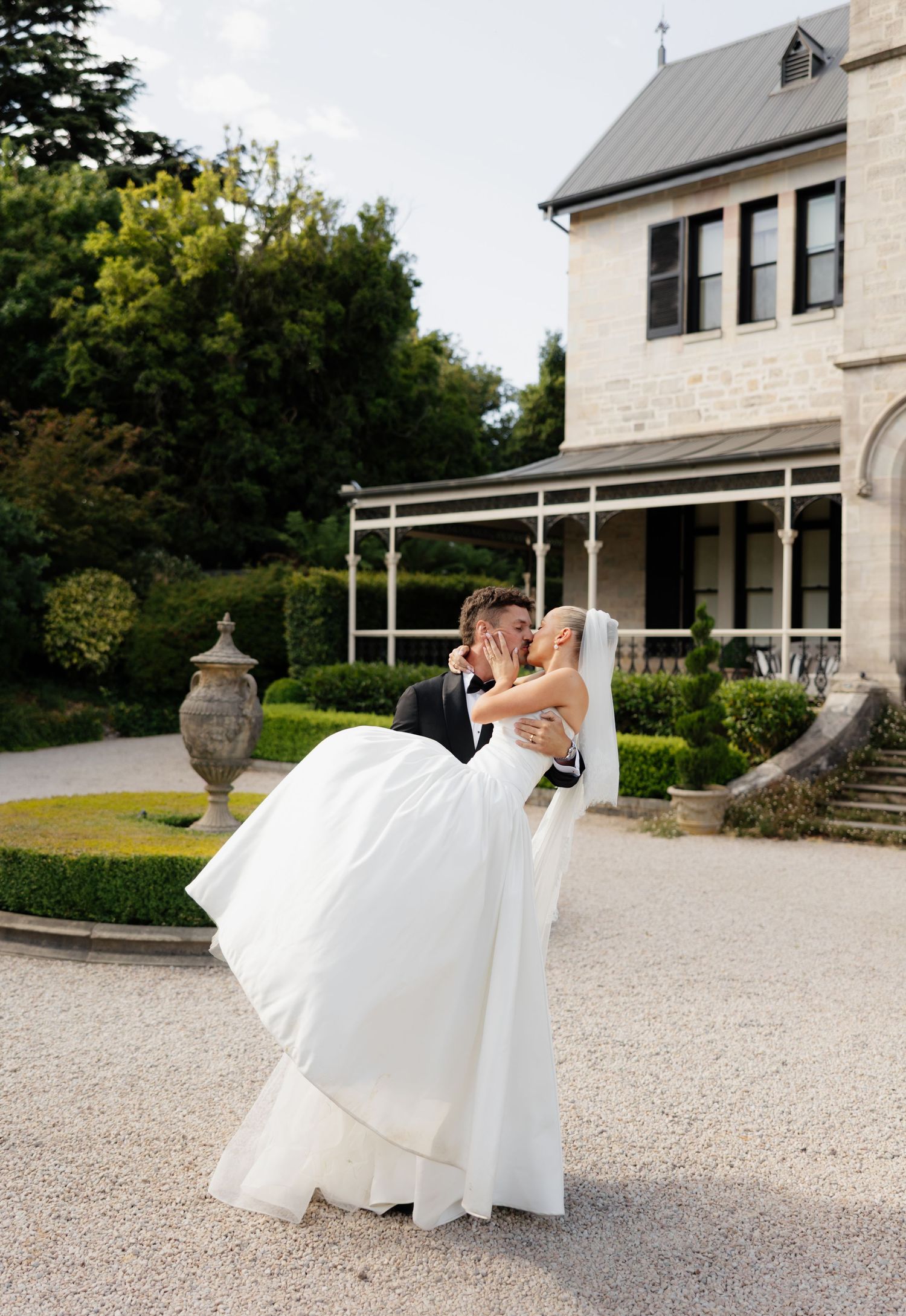 A sequence of romantic wedding photos showing a couple in formal attire dipping and dancing on a stone driveway.