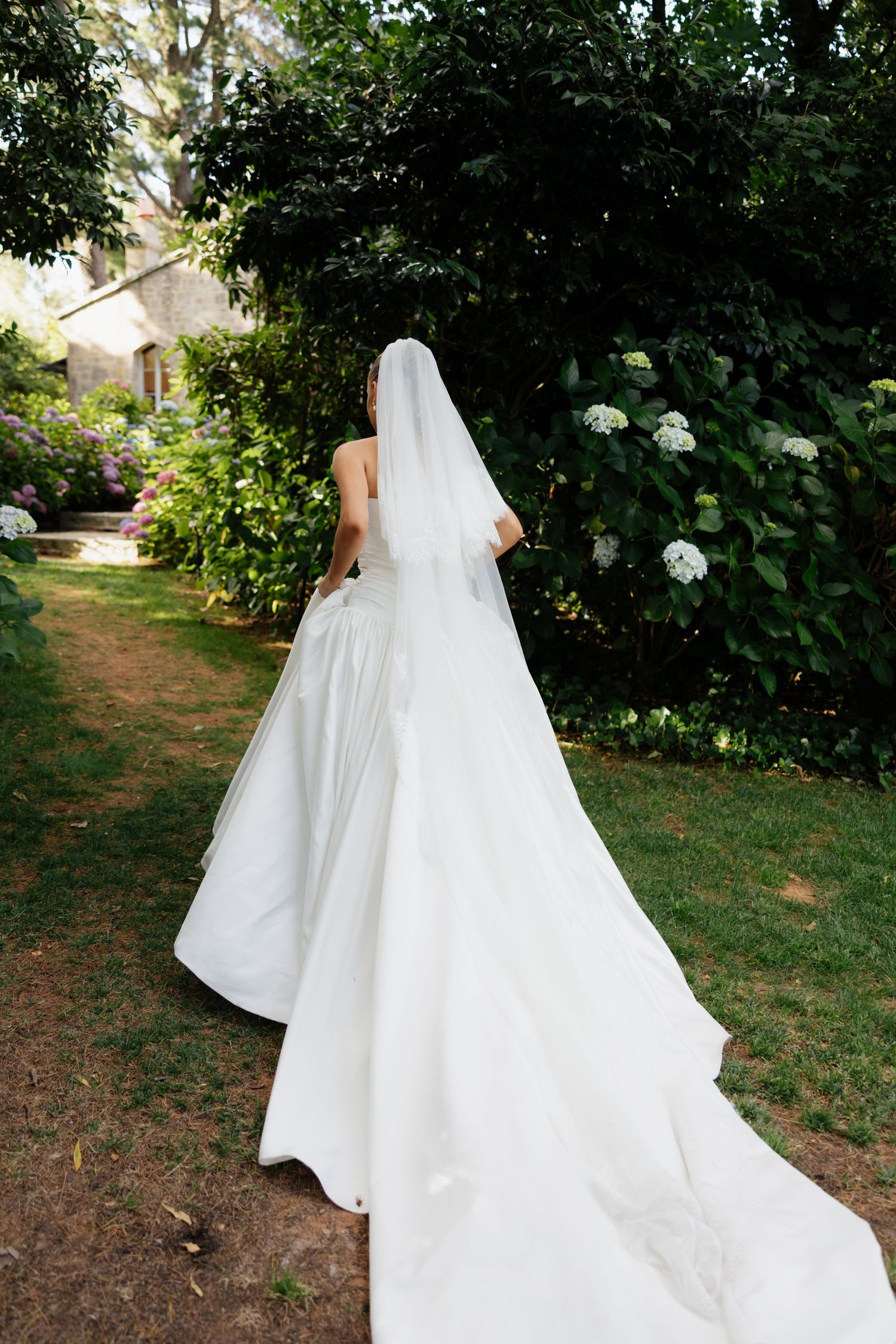 A flowing white wedding dress with a long veil captured in a garden setting from multiple angles.