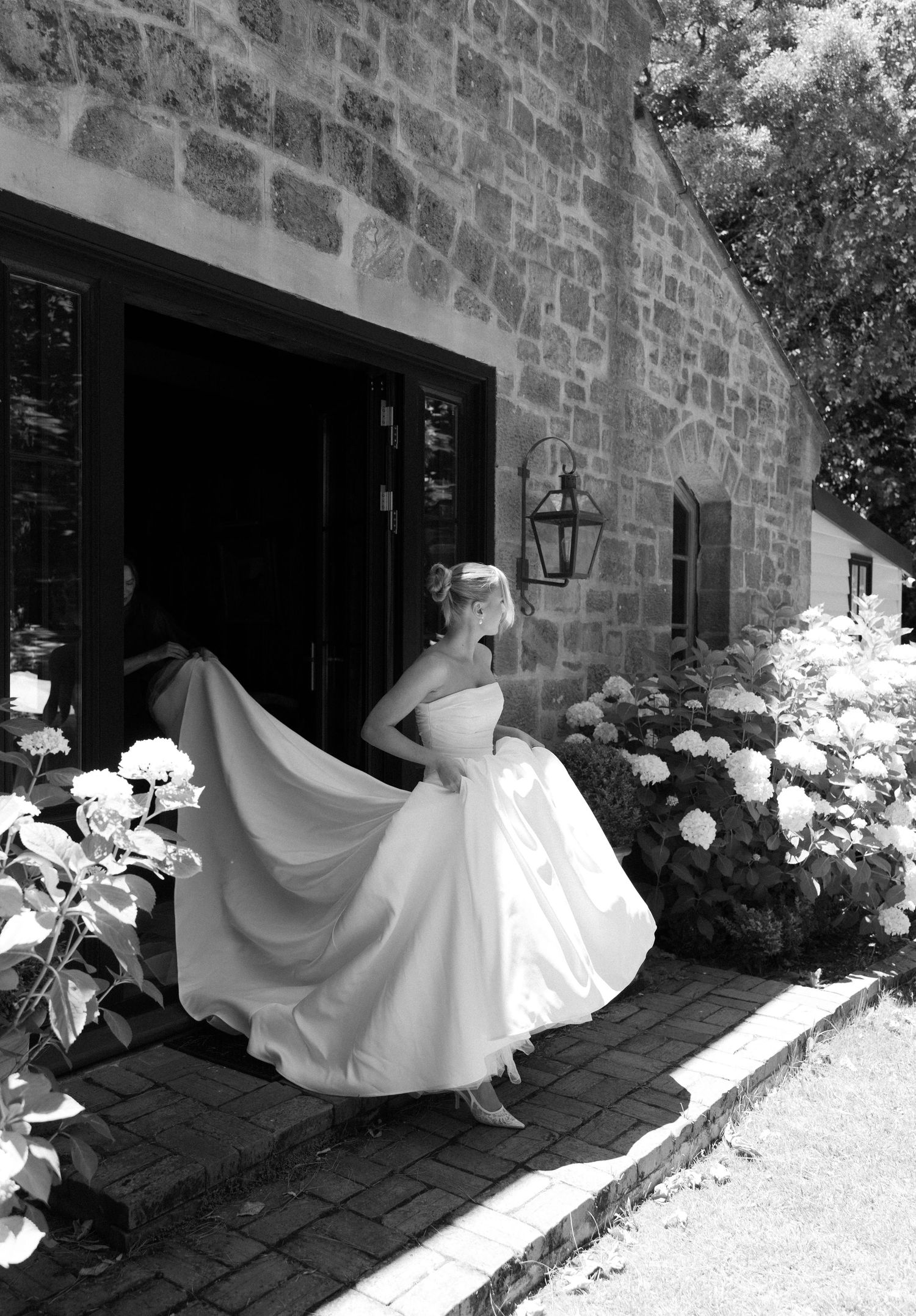 Black and white photos of a flowing white wedding dress twirling against a stone building backdrop.