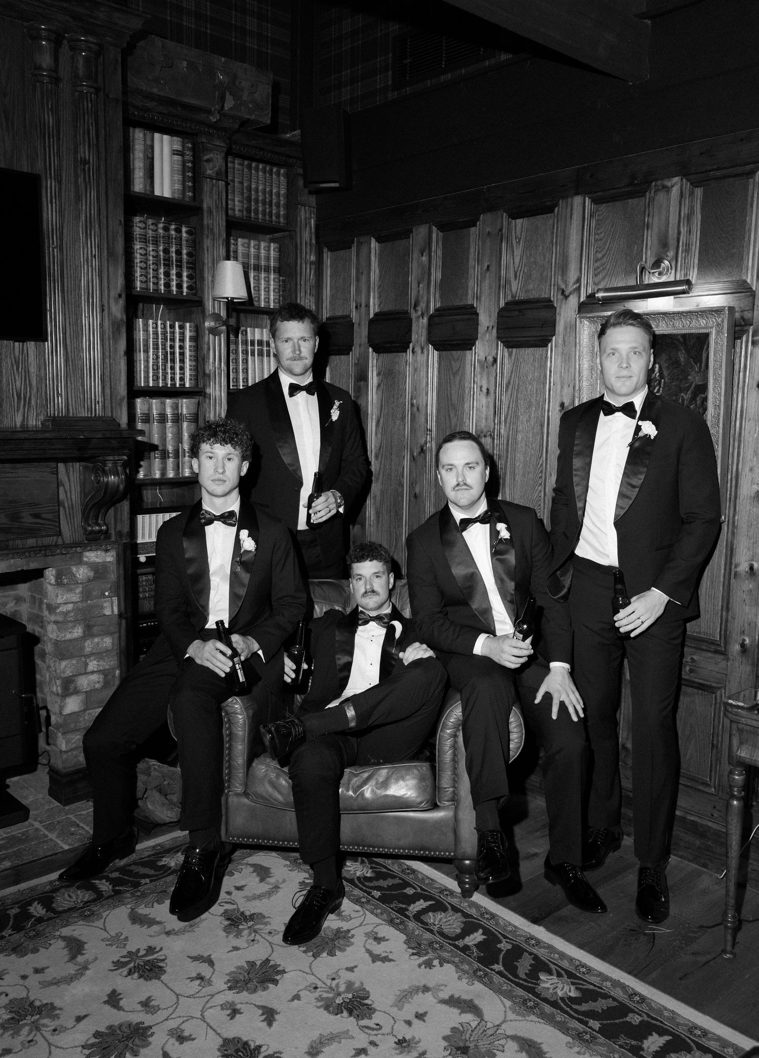 A series of four black and white photos showing a group in formal attire posing playfully in an indoor setting.