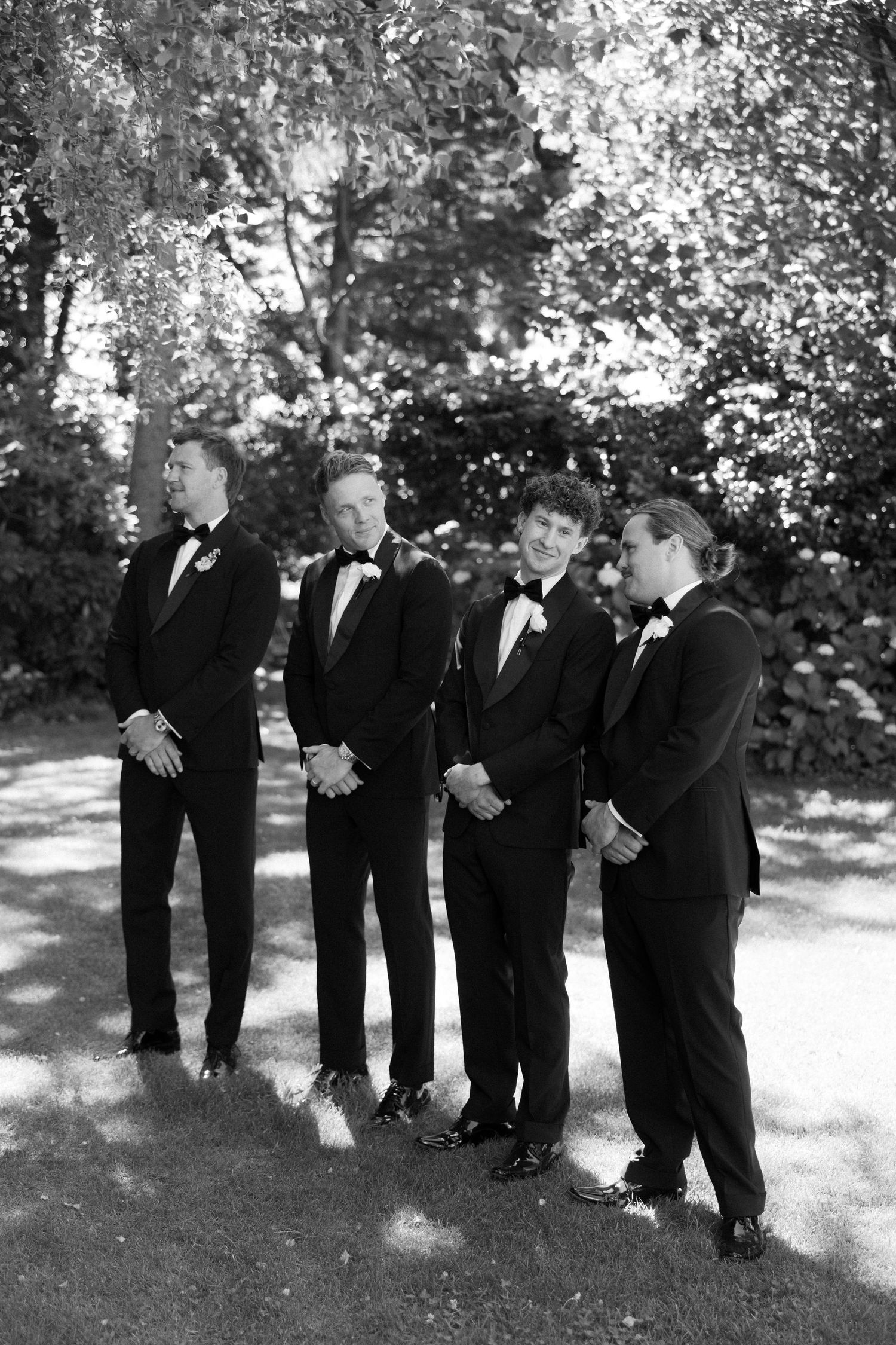A series of black and white photos showing groomsmen in tuxedos posing playfully outdoors at a wedding.