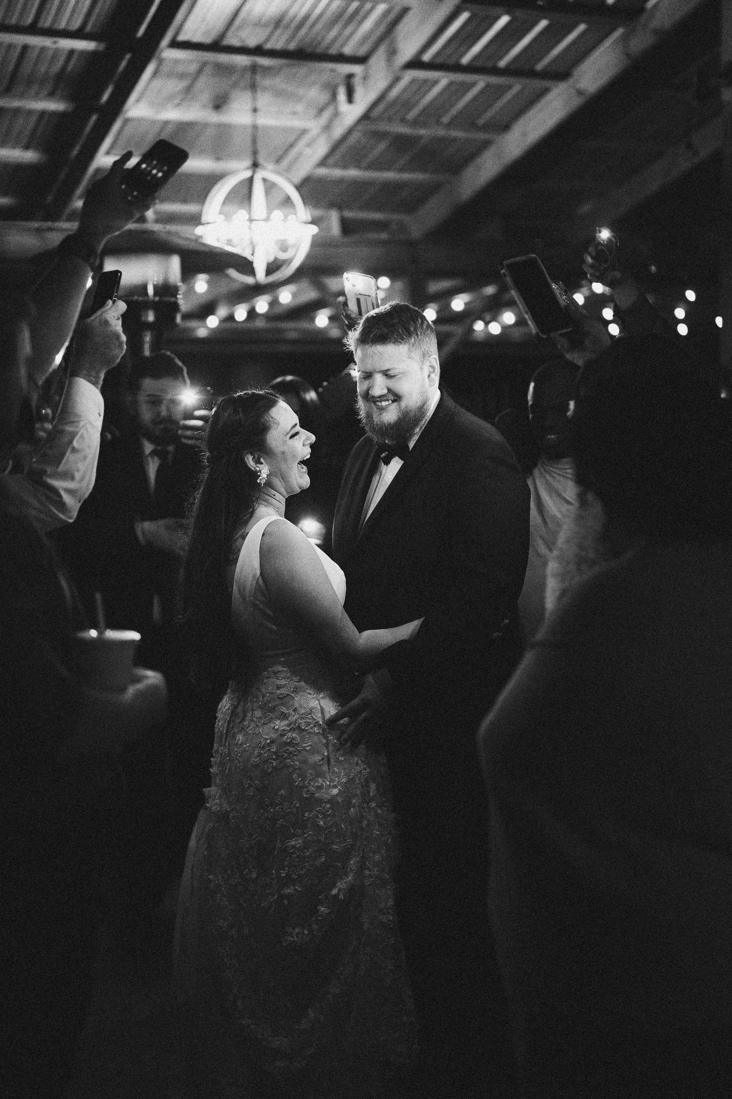 A couple shares a romantic moment on the dance floor under twinkling lights and a disco ball at their wedding reception.
