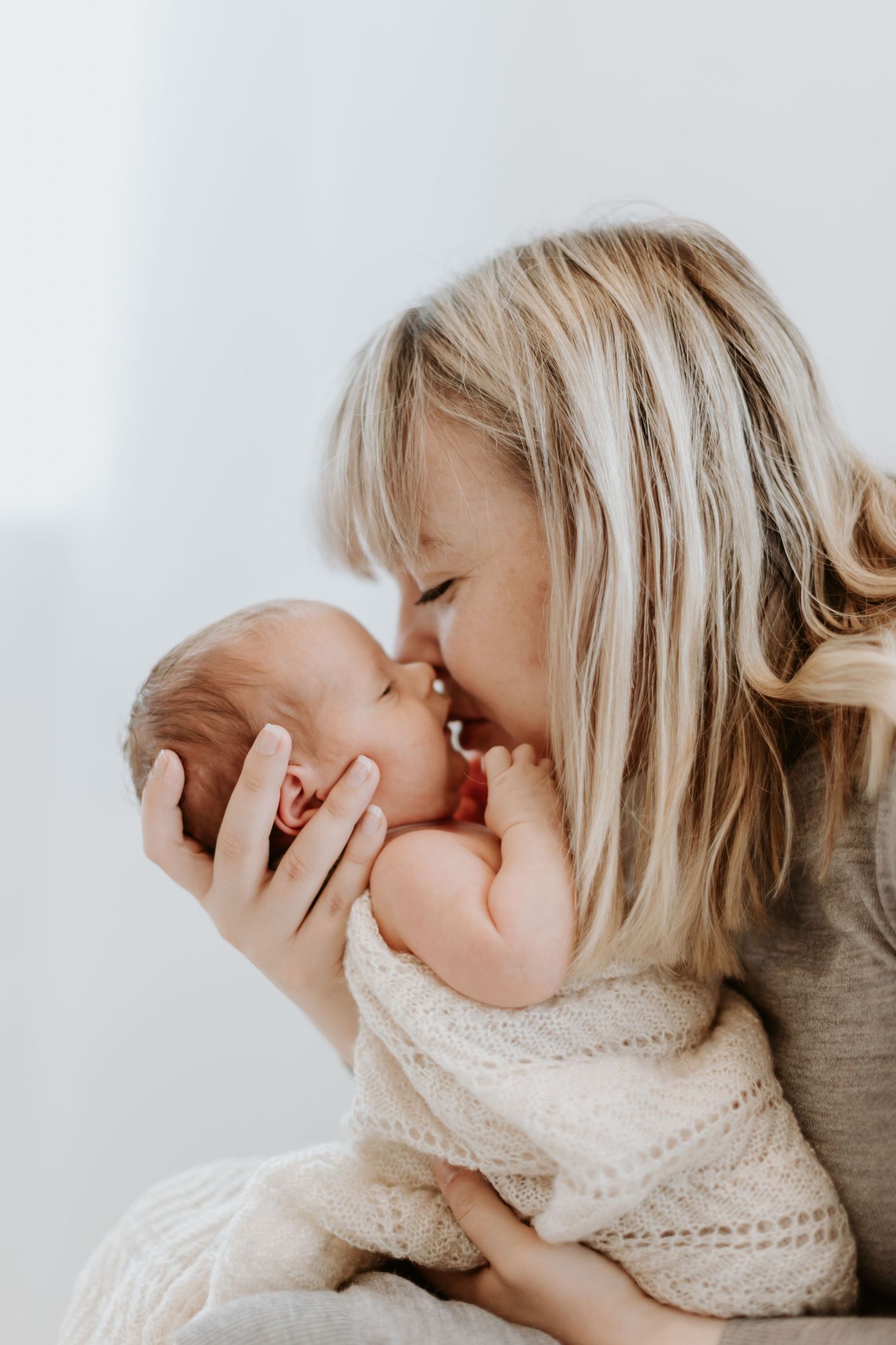 A tender moment captured in a series of four white-toned photos showing a parent embracing their young child.