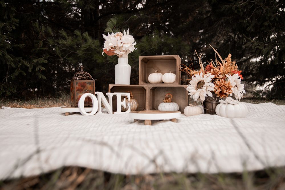 Wooden crates and white letters spell ONE among dried flowers in a rustic outdoor photo setup.