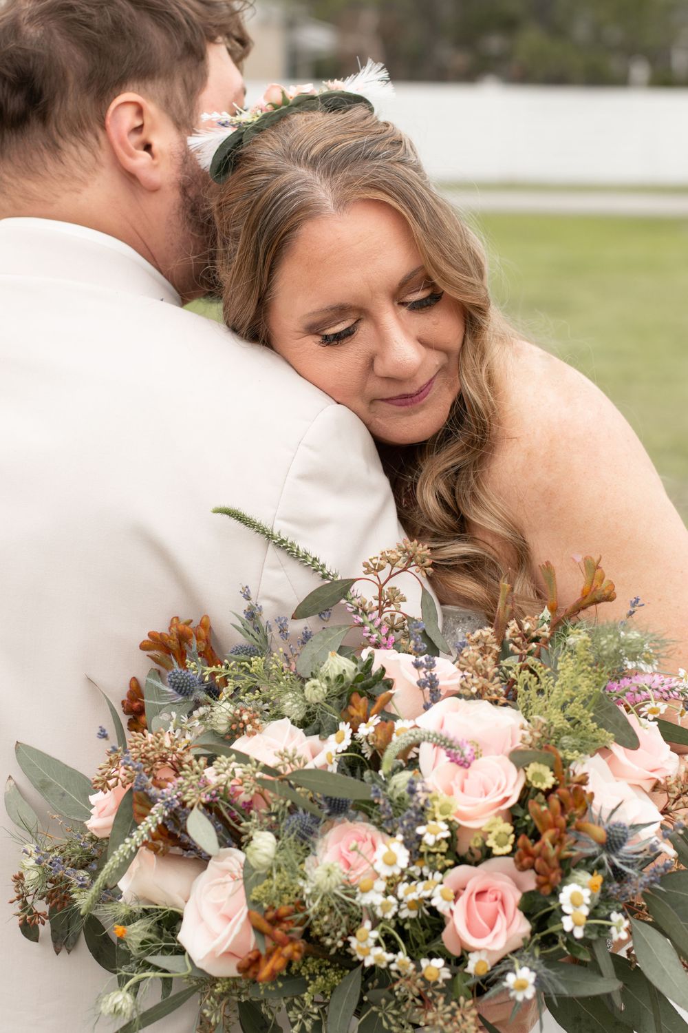 A tender wedding moment with a beautiful bouquet of pink roses and greenery.