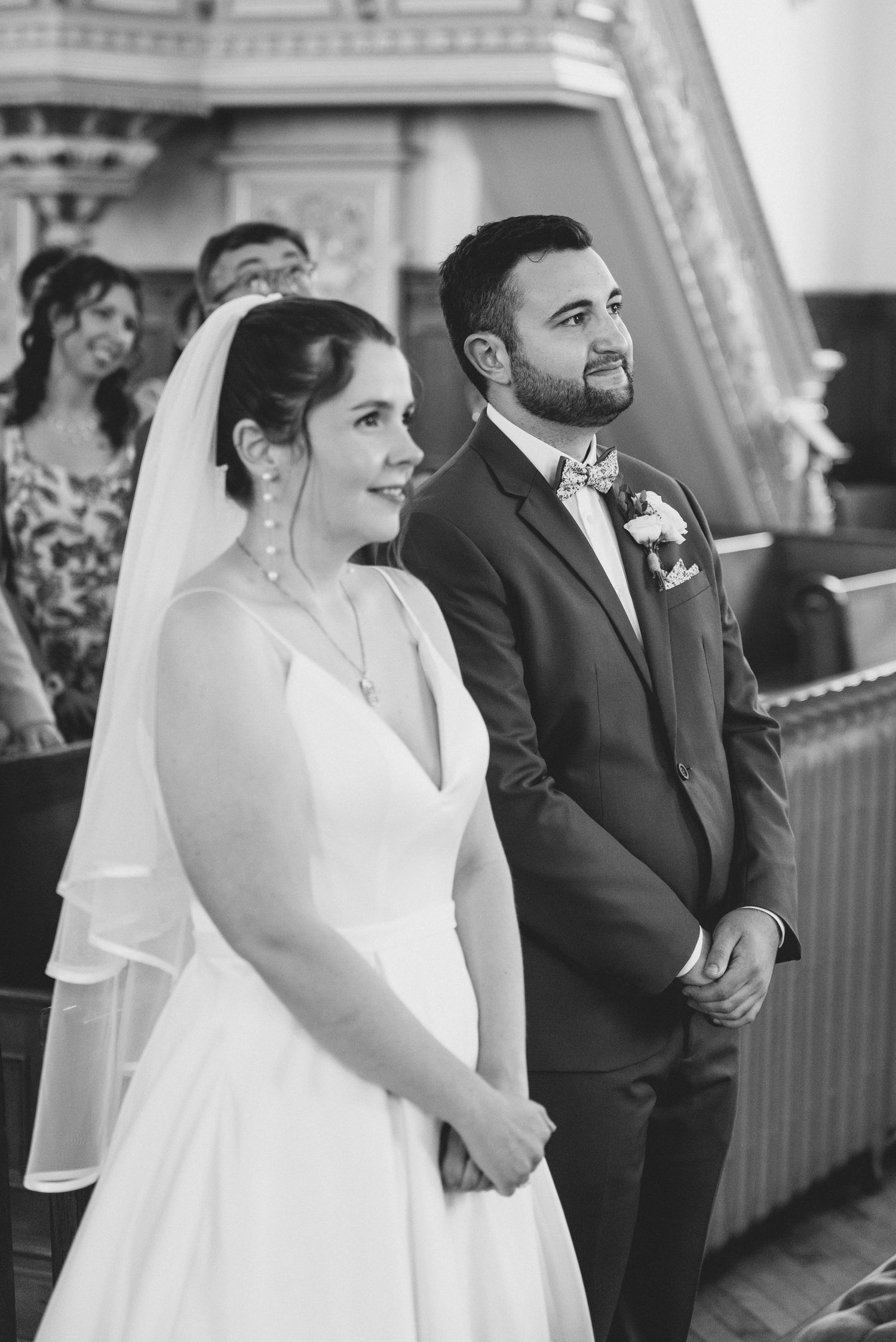 A wedding ceremony moment showing a couple standing at the altar in traditional attire with classical architecture behind them.