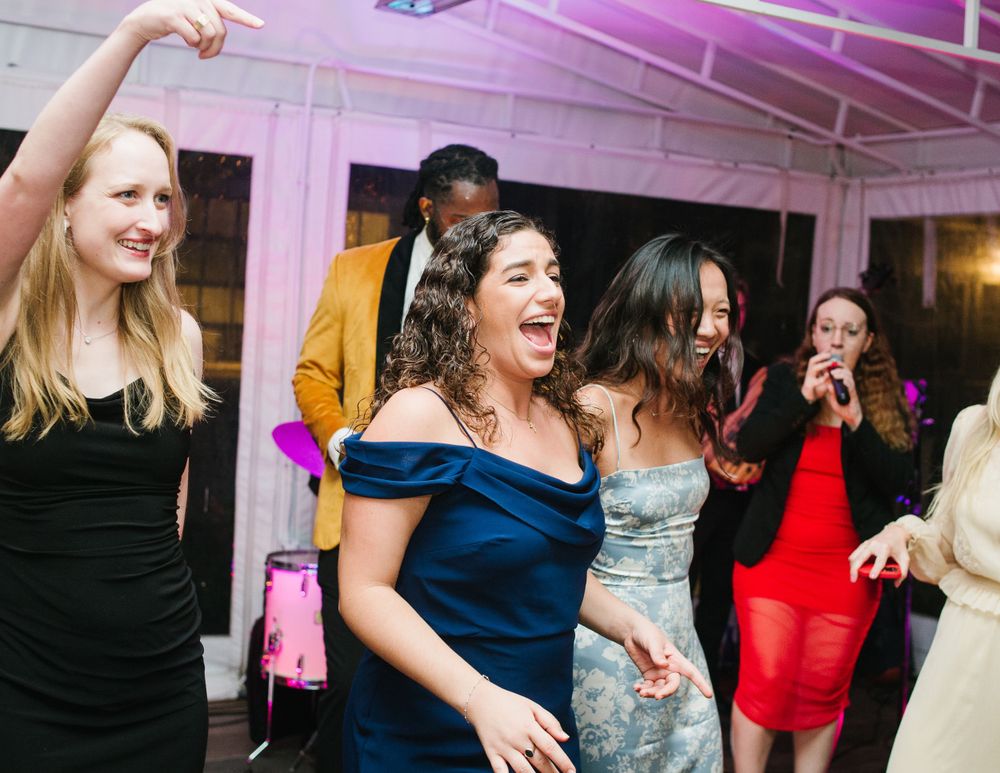 Lively wedding reception with a packed dance floor, colorful lights, laughing guests.