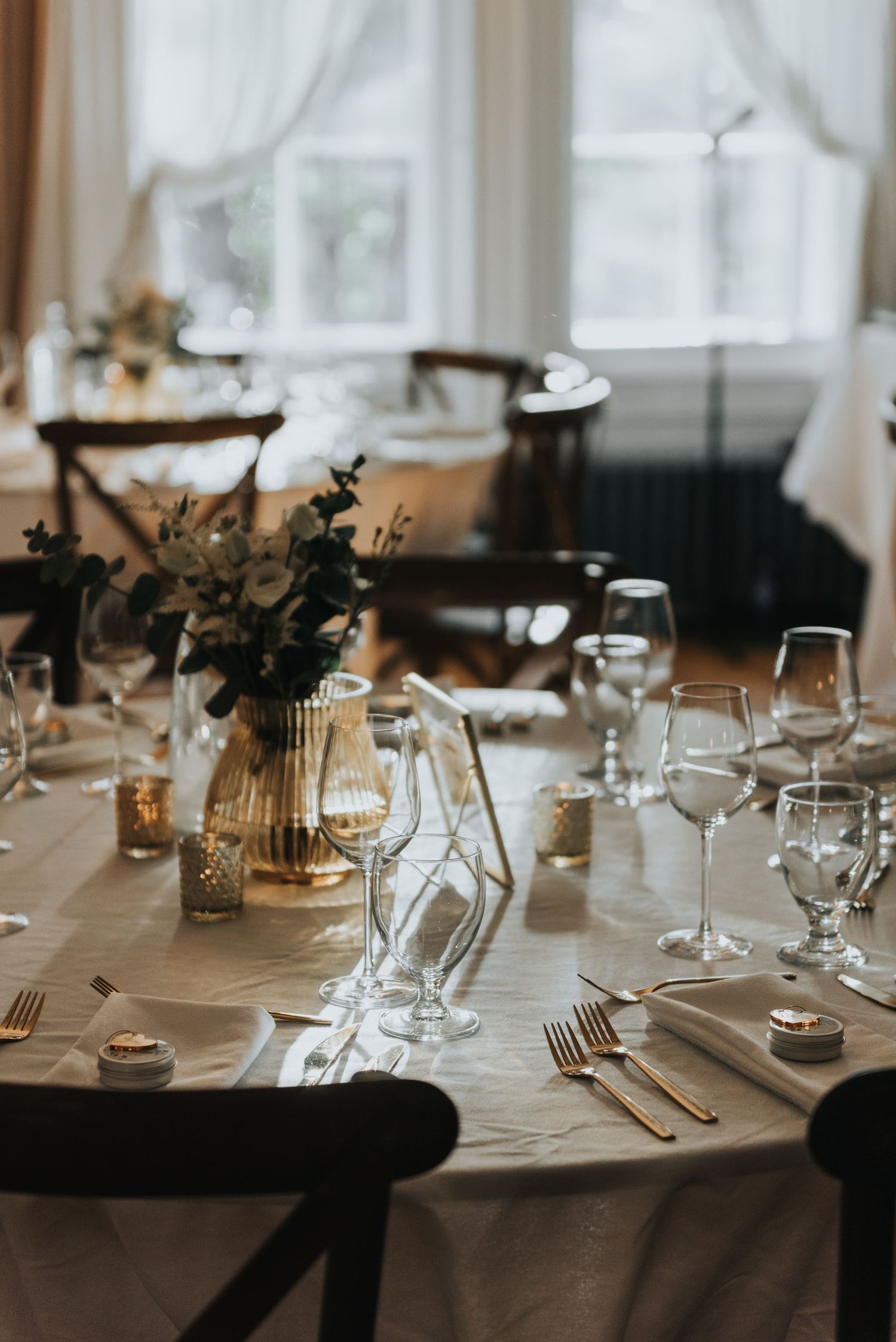 Close-up of an elegantly set dining table with glassware, candles, and rustic floral centerpieces.