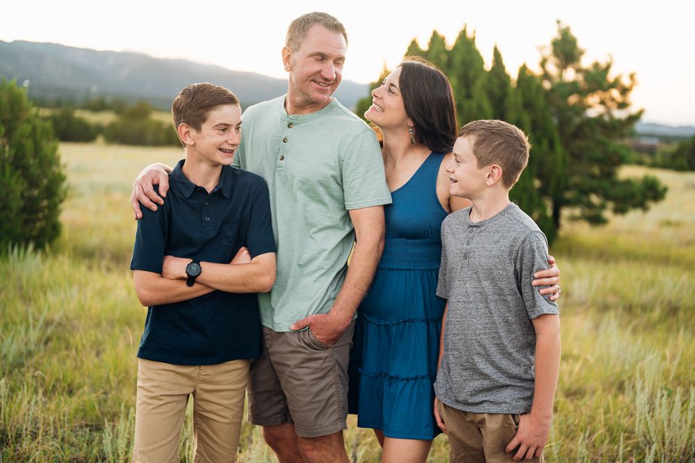 A family shares joyful moments together while posing outdoors in a natural setting at sunset.