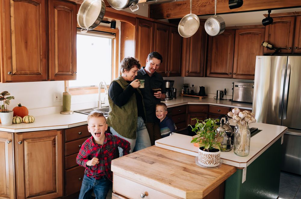 Family spending time together in a warm wooden kitchen with butcher block island and stainless steel appliances.