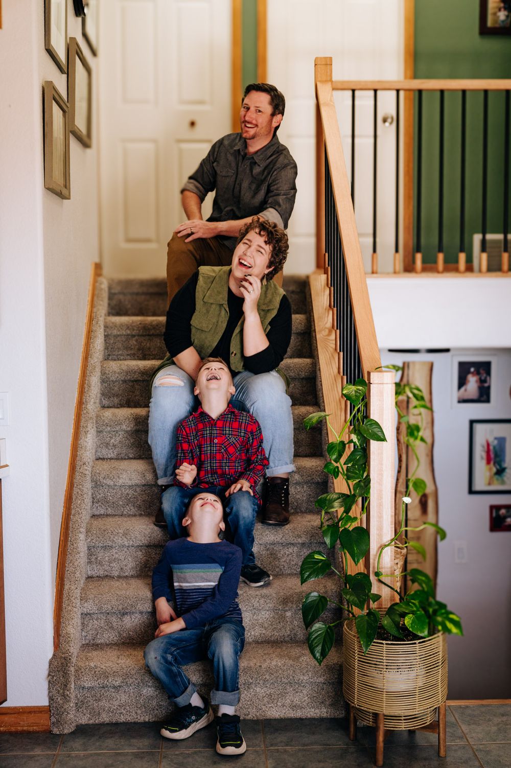 Two people sit together on carpeted stairs in a home interior, sharing a joyful candid moment.