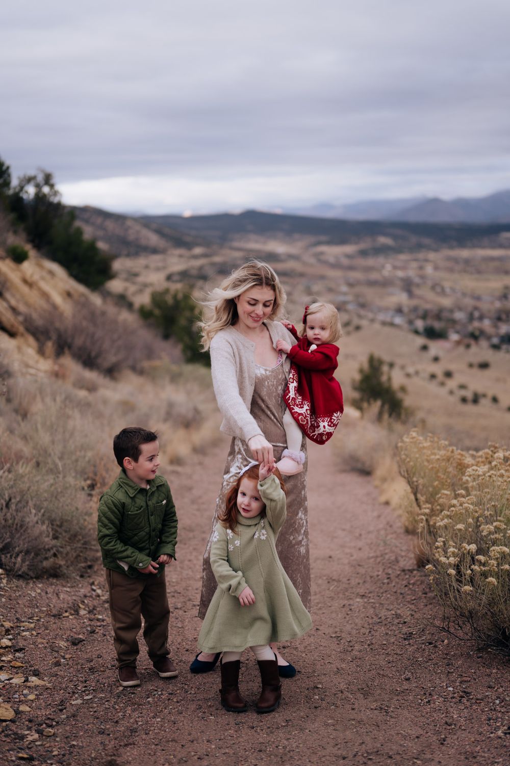 A family walks along a dirt path through rolling hills on an overcast day.