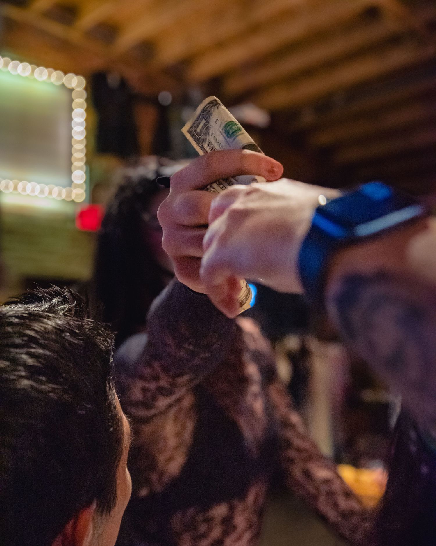 Drag queen Ivy Profen takes a dollar from crowd during performance. Close up of hands exchanging dollar.