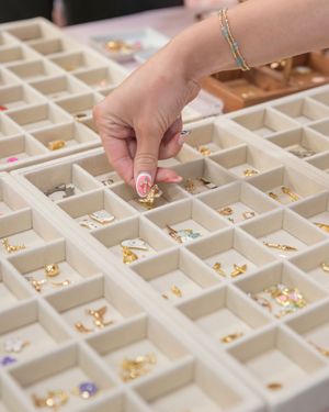 A close up of hands picking jewelry charms from an assortment at a pop up market event