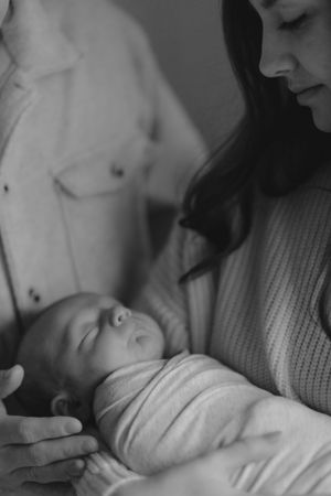 A tender black and white photograph shows a sleeping baby being cradled in a sweater-clad embrace.