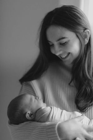 A tender black and white portrait showing a mother looking lovingly at her newborn baby in her arms.