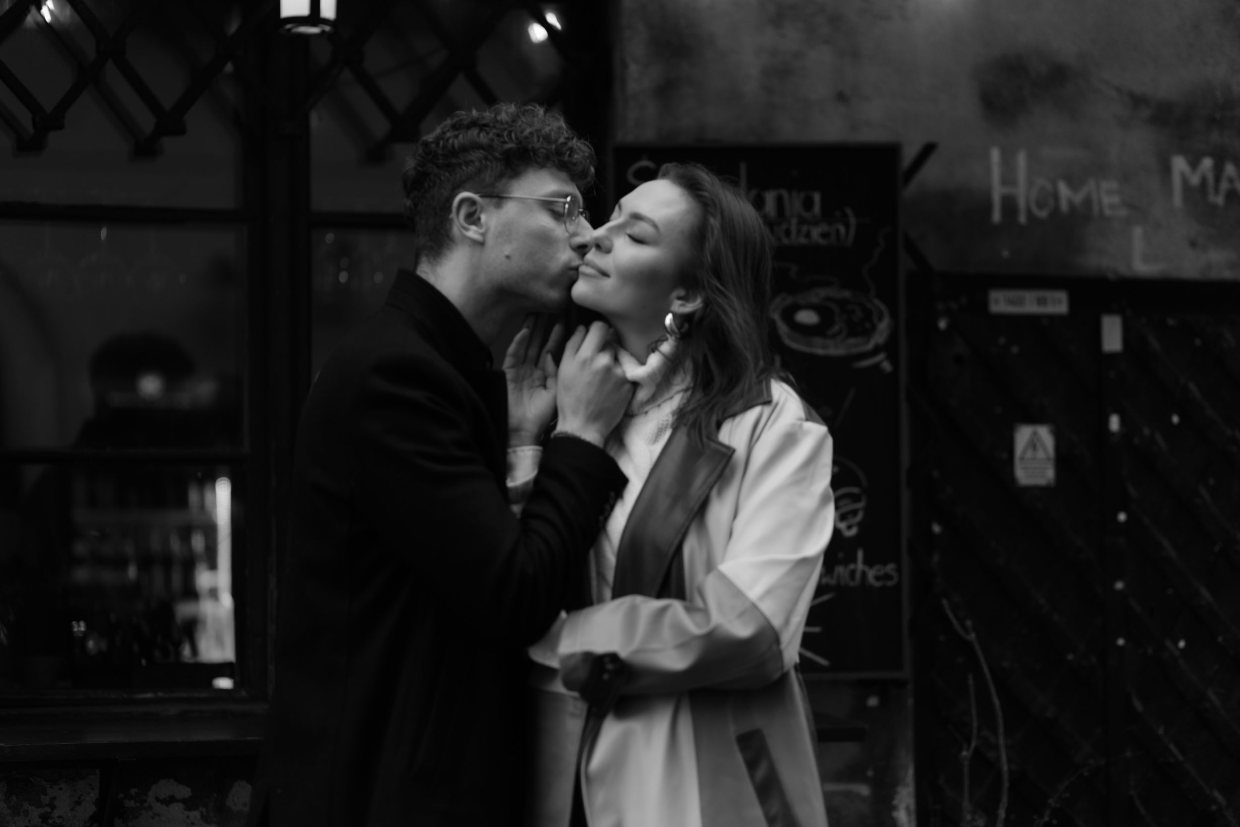 A romantic black and white photograph showing an intimate moment between two people on a city street at night.
