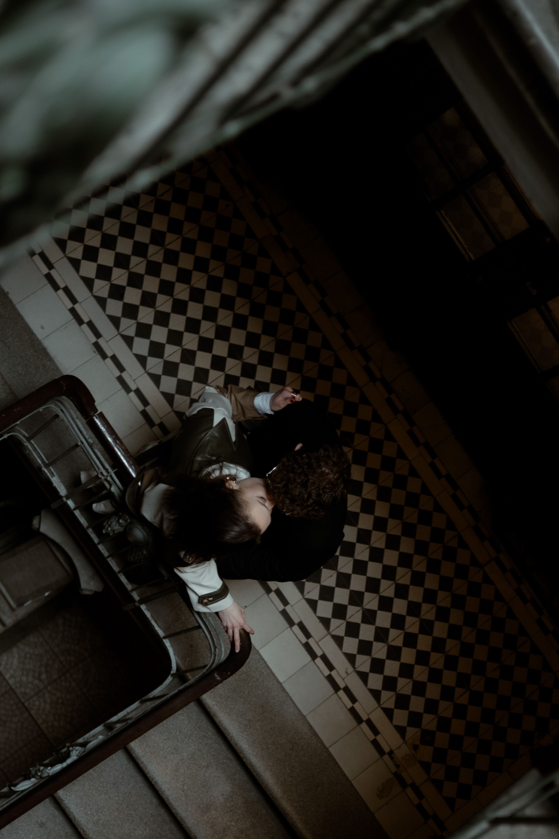 A moody overhead shot on a checkered floor shows an artistic black and white composition with dramatic shadows.