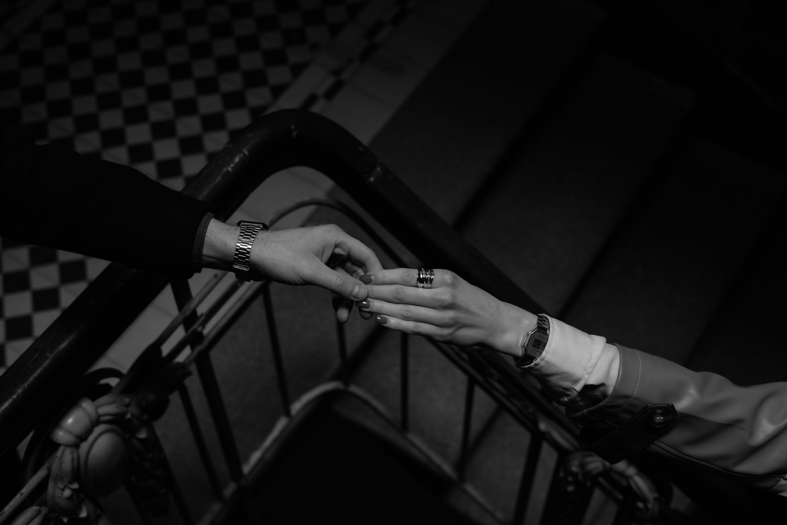 A black and white photograph shows hands adjusting a microphone stand in a recording studio setting.